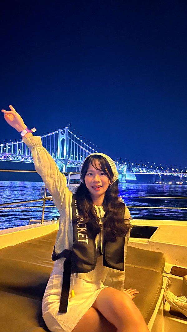 在夜景前的遊船甲板上舉手的遊客