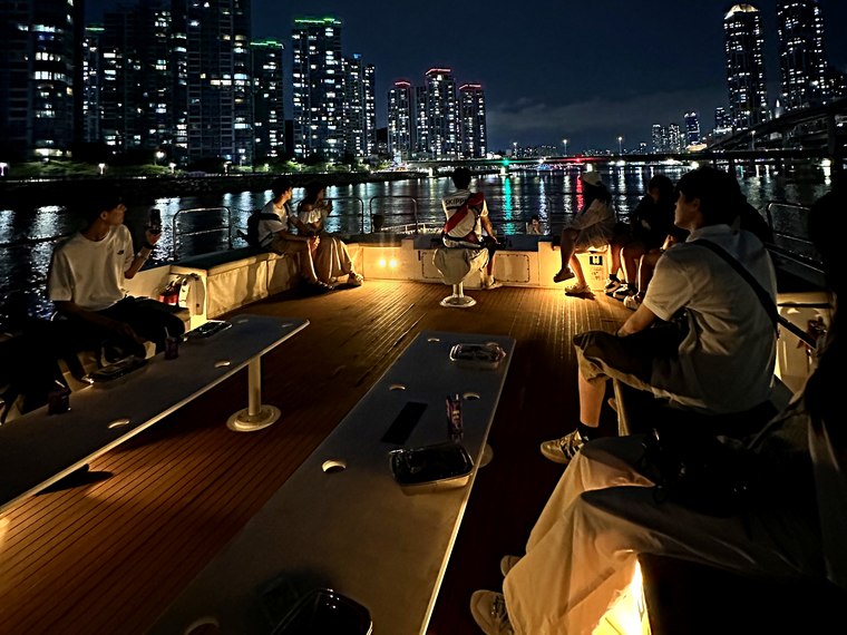 以夜景為背景聚在甲板上的團體遊客