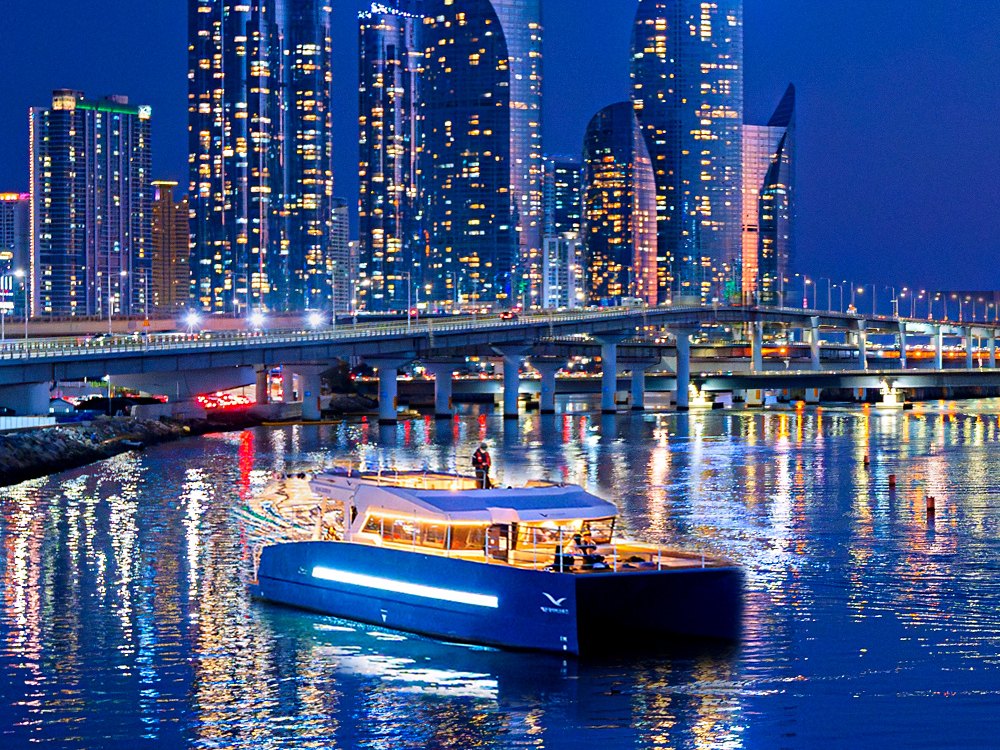 在 Marine City 夜景前駛過水營江的海雲台河川遊船