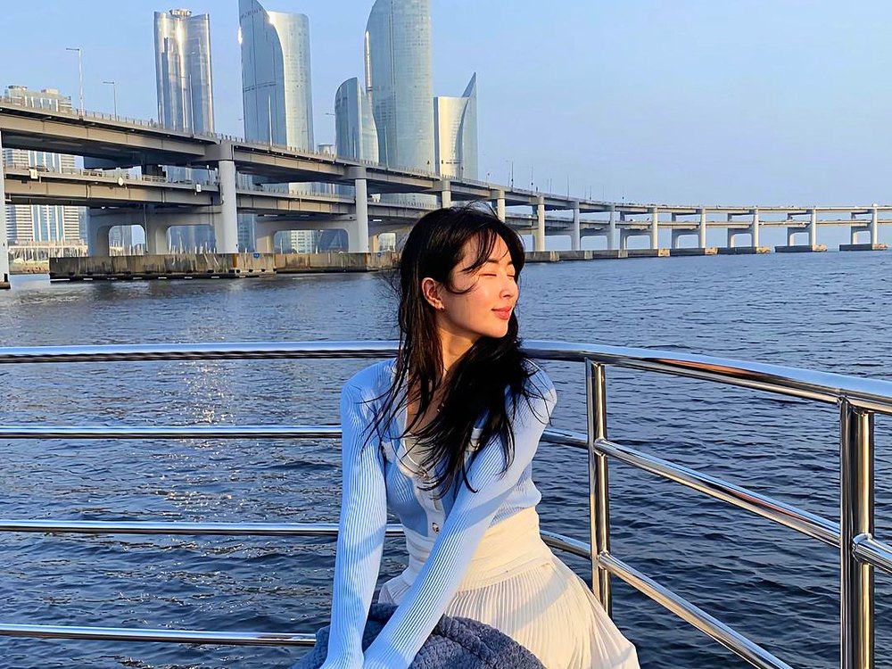 以廣安大橋和 Marine City 為背景坐在遊船欄杆上的遊客